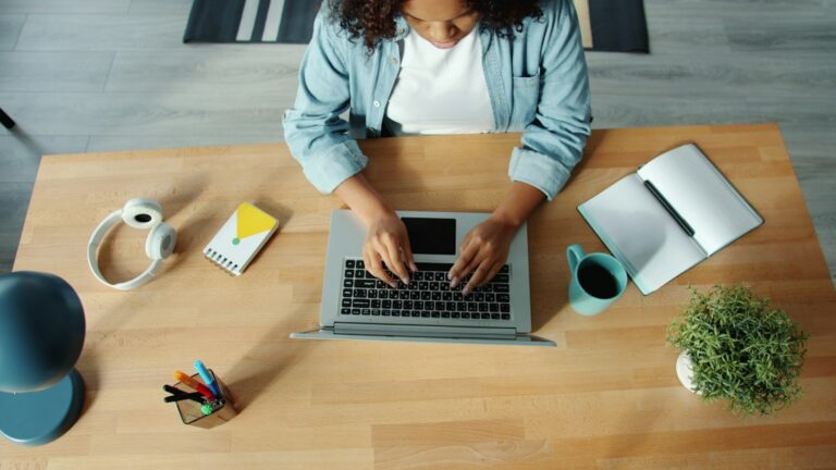 Writer typing on a laptop at a modern wooden desk